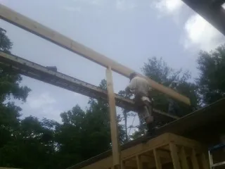 Carpenter setting a ridge beam over a new addition frame — Ice Dam Removal by Roofing Brothers in Waldorf