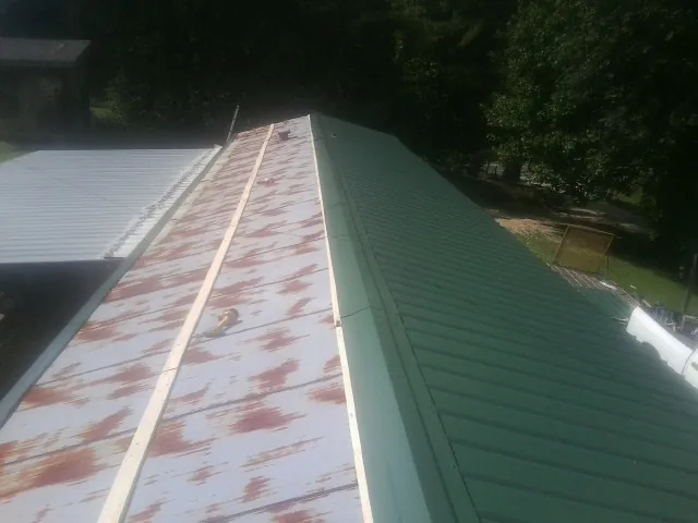 Old rusted panels beside newly installed green metal roofing — Wind Damage Roof Repair by Roofing Brothers in Waldorf