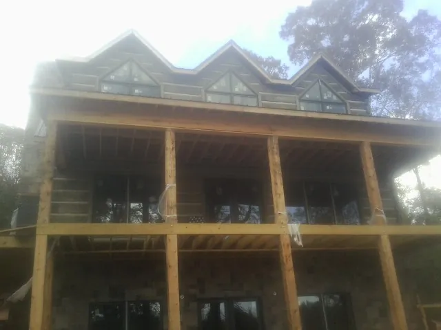 Dormers and porch framing on a large log home under construction — Roof Coating work by our crew in Waldorf