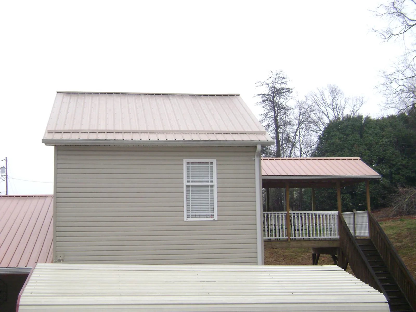 Tan metal roofs on a two story addition and attached porch, from a Roof Replacement job in Waldorf