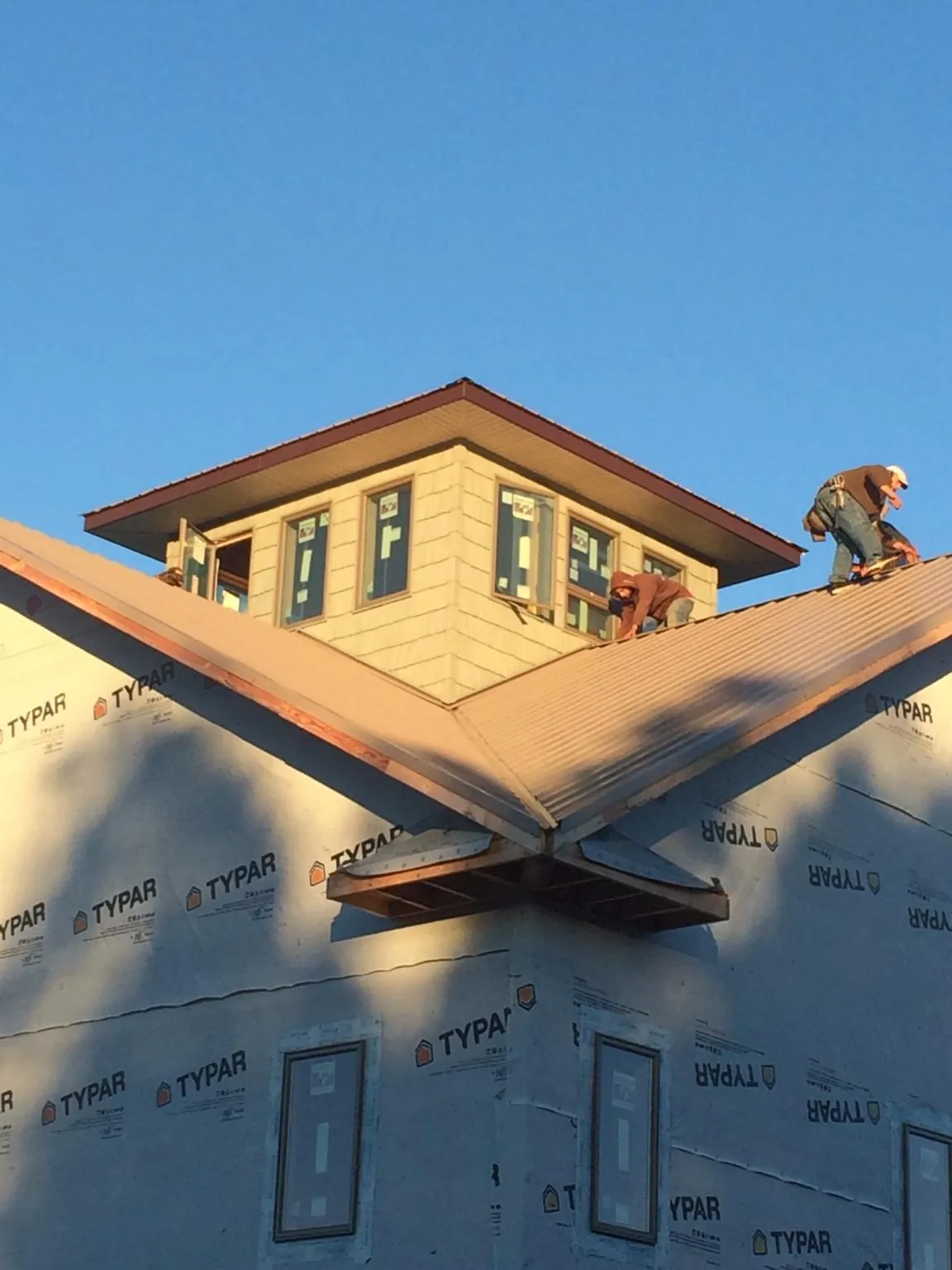 Roofers working around a rooftop cupola on a new metal roof at sunset — Roof Waterproofing in Waldorf by Roofing Brothers